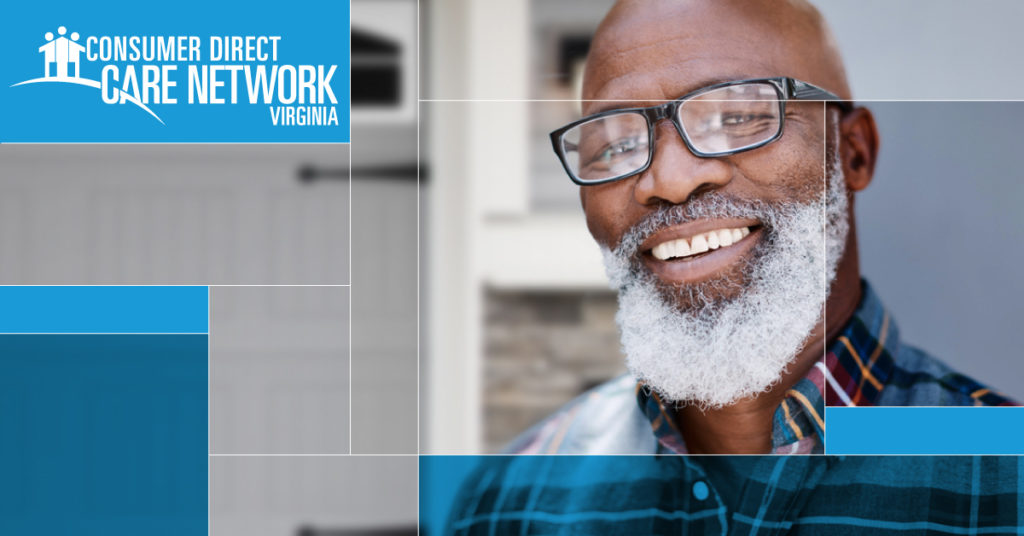 African American man with a gray beard and glasses smiling in front of his house.