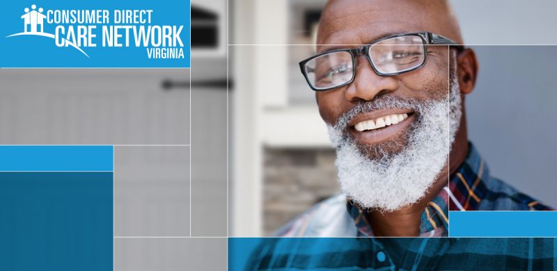 African American man with a gray beard and glasses smiling in front of his house.